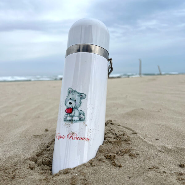 Thermos blanc planté dans le sable avec une illustration d'un chien assis avec un coeur dans la gueule